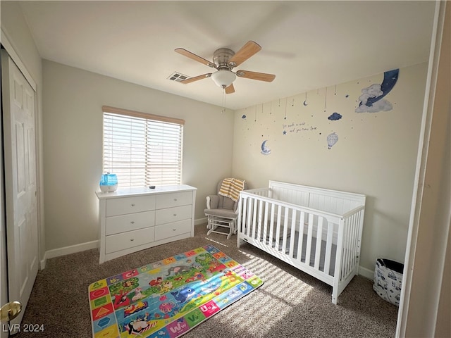 bedroom featuring a closet, ceiling fan, dark carpet, and a crib