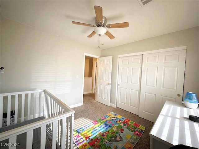 bedroom with a closet, carpet floors, a crib, and ceiling fan