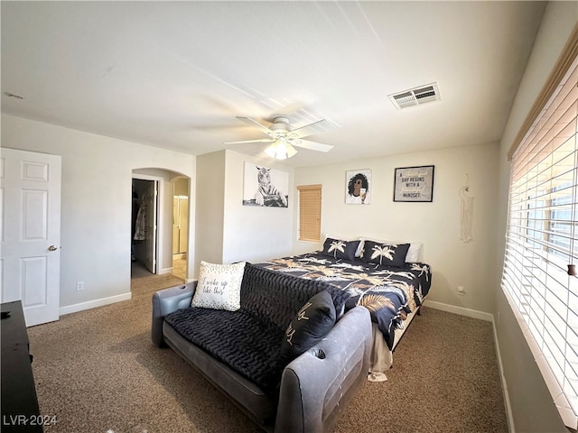 bedroom featuring a walk in closet, carpet flooring, and ceiling fan