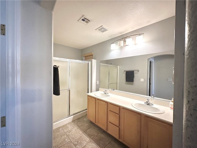 bathroom with a shower with door, a textured ceiling, and vanity