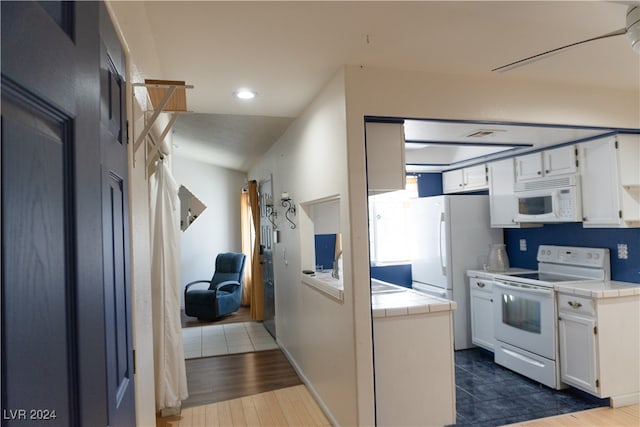 kitchen featuring tile countertops, lofted ceiling, white cabinets, hardwood / wood-style flooring, and white appliances