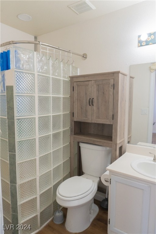 bathroom featuring walk in shower, vanity, hardwood / wood-style flooring, and toilet