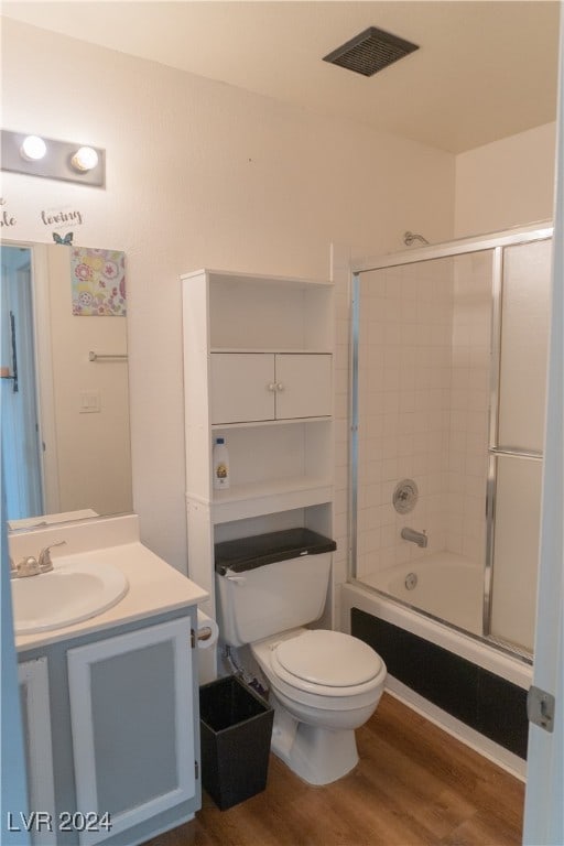 full bathroom featuring toilet, vanity, wood-type flooring, and enclosed tub / shower combo