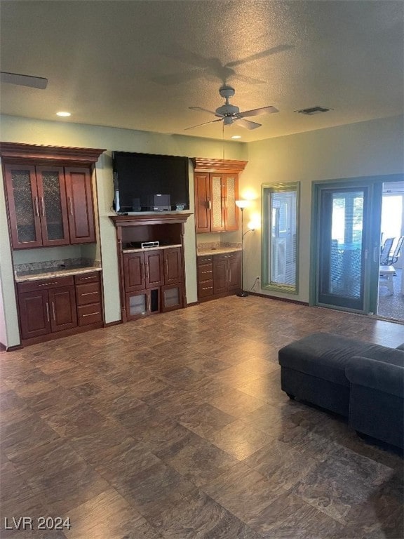 living room featuring ceiling fan and a textured ceiling