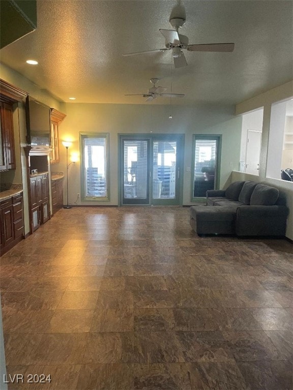 living room featuring a wealth of natural light, ceiling fan, and a textured ceiling