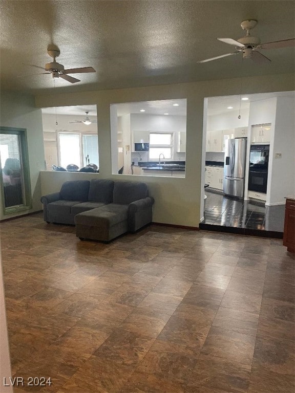 living room with a textured ceiling, ceiling fan, and sink