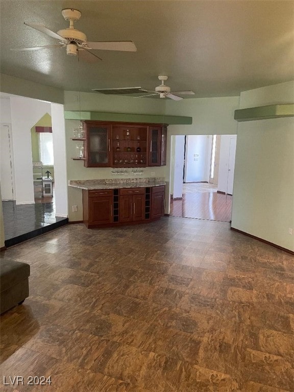 unfurnished living room featuring ceiling fan and dark wood-type flooring