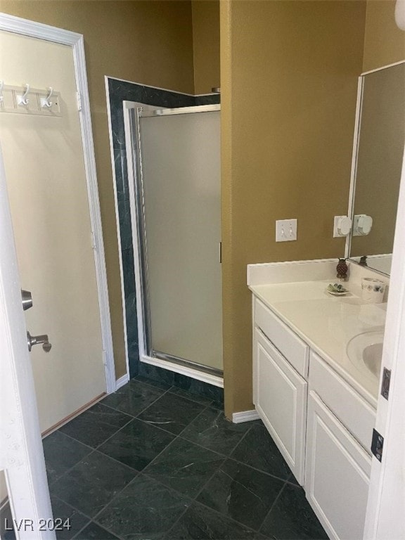 bathroom with a shower with door, vanity, and tile patterned flooring