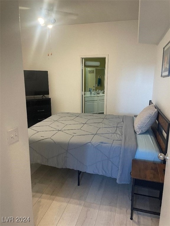 bedroom with ceiling fan, light wood-type flooring, and ensuite bath