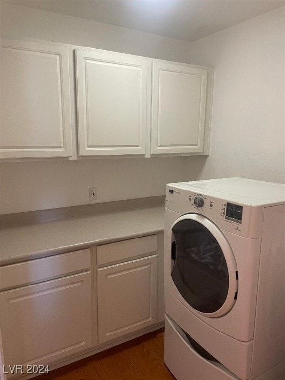 washroom featuring washer / clothes dryer, dark wood-type flooring, and cabinets