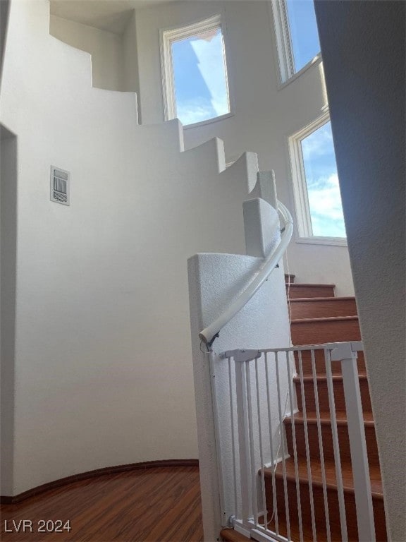 stairway featuring wood-type flooring and a towering ceiling