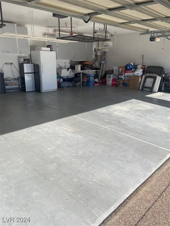 garage with white refrigerator, a garage door opener, and fridge