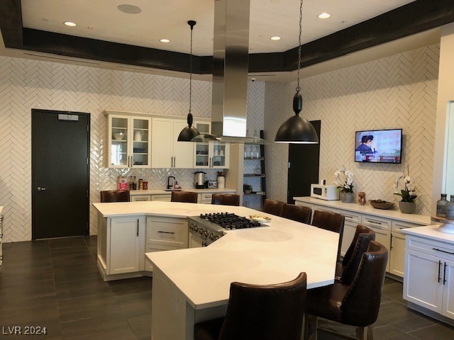 kitchen with a breakfast bar, a center island, pendant lighting, and white cabinets