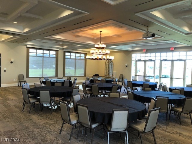 dining space featuring french doors, a tray ceiling, coffered ceiling, dark wood-type flooring, and a notable chandelier