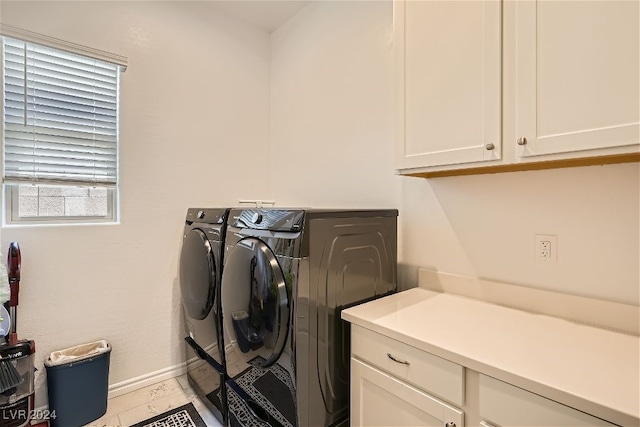 clothes washing area with cabinets, separate washer and dryer, and light tile patterned floors