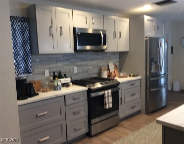 kitchen with light hardwood / wood-style floors, tasteful backsplash, and stainless steel appliances