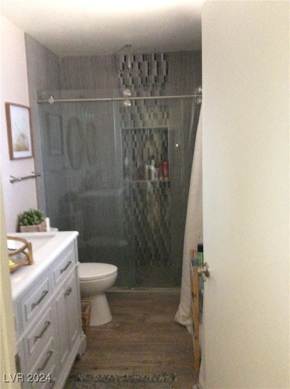 bathroom featuring vanity, toilet, hardwood / wood-style flooring, and walk in shower