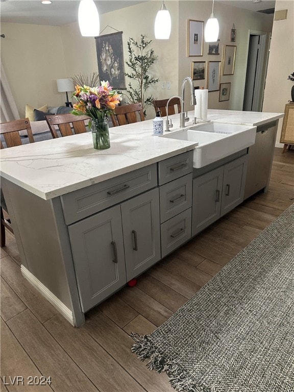 kitchen with gray cabinets, a kitchen island with sink, decorative light fixtures, and dark hardwood / wood-style floors