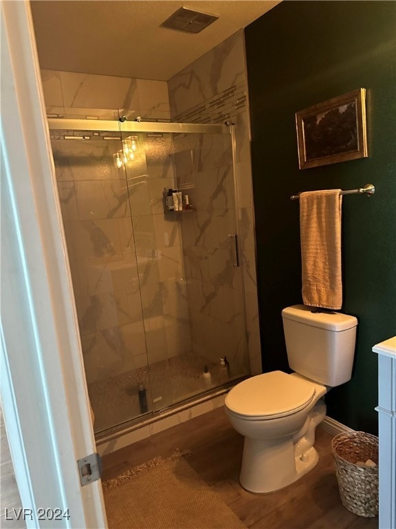 bathroom featuring vanity, hardwood / wood-style flooring, toilet, and an enclosed shower