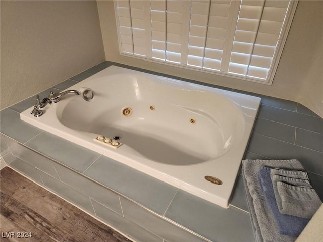 bathroom featuring tiled bath and hardwood / wood-style floors