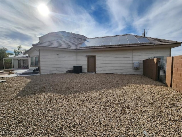 rear view of house featuring solar panels and central air condition unit