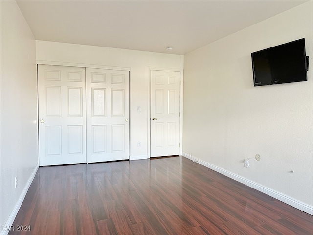 unfurnished bedroom with dark wood-type flooring and a closet