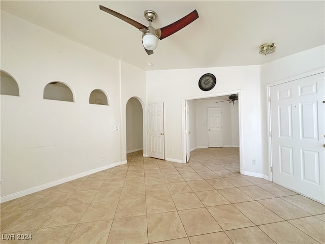 empty room with lofted ceiling, ceiling fan, and light tile patterned floors