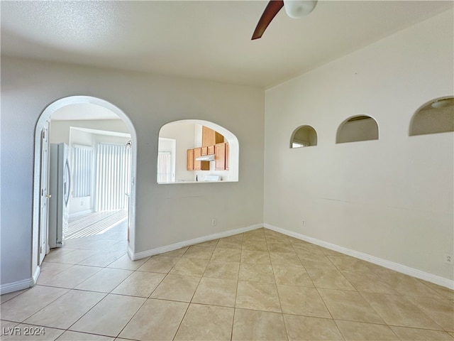 tiled empty room featuring ceiling fan