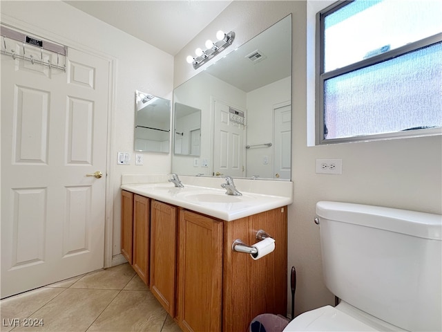 bathroom with toilet, vanity, and tile patterned flooring