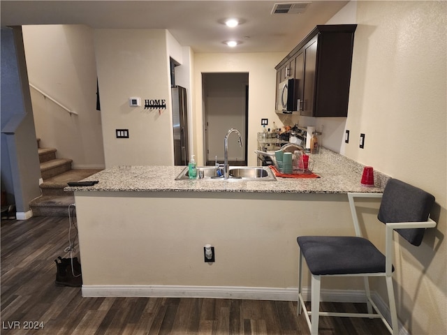 kitchen with kitchen peninsula, sink, dark brown cabinets, and appliances with stainless steel finishes