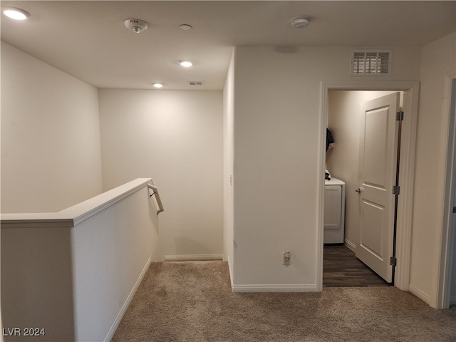 hall featuring washer / dryer and dark colored carpet