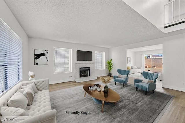 living room with a textured ceiling, a fireplace, and wood-type flooring