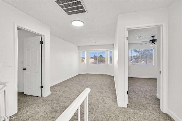 corridor featuring light colored carpet and a textured ceiling