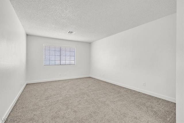 carpeted empty room featuring a textured ceiling