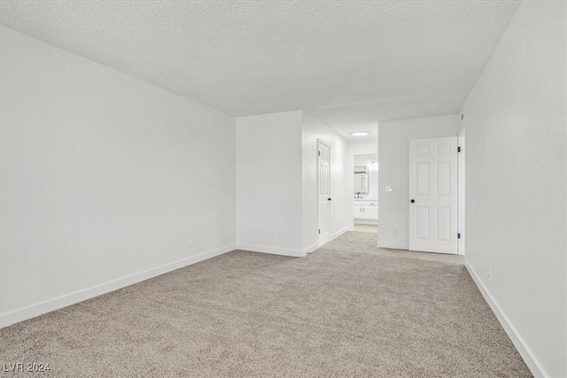 unfurnished room with a textured ceiling and light carpet