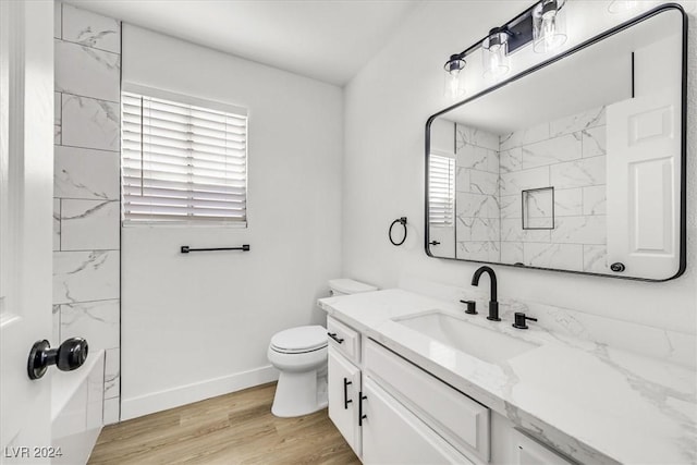 bathroom with hardwood / wood-style flooring, toilet, vanity, and walk in shower