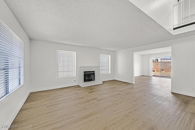 unfurnished living room with light hardwood / wood-style floors, a textured ceiling, and a fireplace