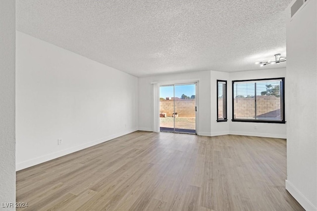 empty room featuring light wood-type flooring and a textured ceiling