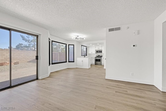 unfurnished living room featuring sink, a textured ceiling, and light hardwood / wood-style flooring