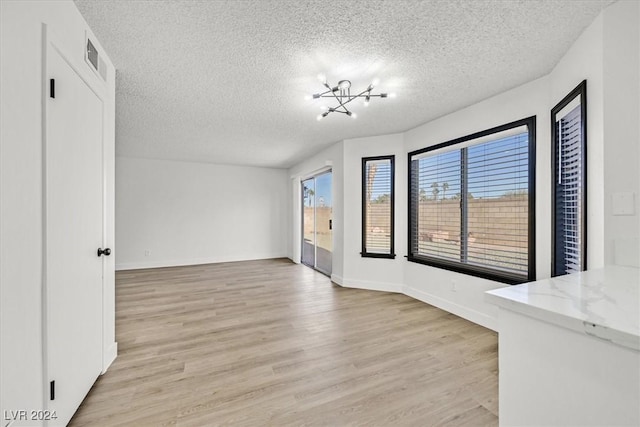 interior space with a textured ceiling, light hardwood / wood-style flooring, and a notable chandelier