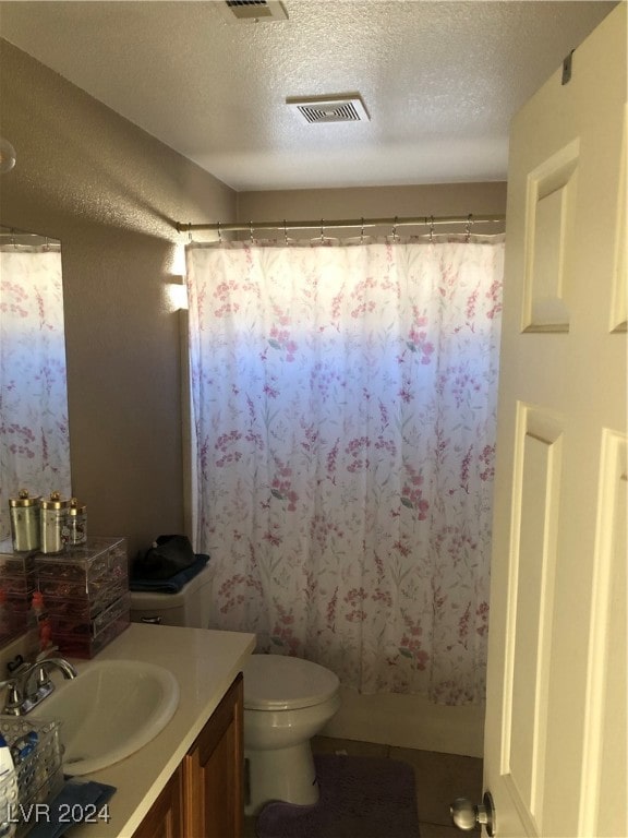 bathroom featuring vanity, a textured ceiling, walk in shower, and toilet