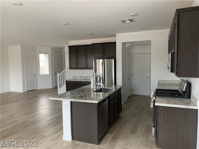 kitchen featuring a center island with sink, light hardwood / wood-style floors, sink, and appliances with stainless steel finishes