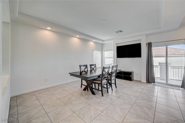 tiled dining space featuring a tray ceiling and a wealth of natural light