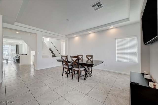 dining room featuring a raised ceiling and light tile patterned floors