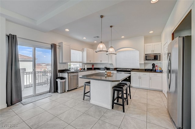 kitchen featuring appliances with stainless steel finishes, a kitchen bar, a kitchen island, decorative light fixtures, and white cabinets