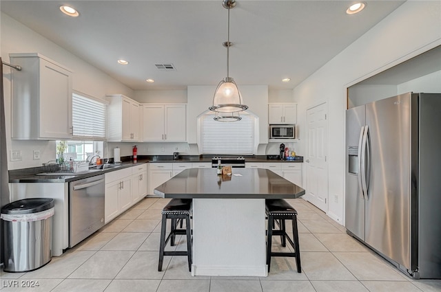 kitchen with appliances with stainless steel finishes, a center island, hanging light fixtures, white cabinets, and a breakfast bar area