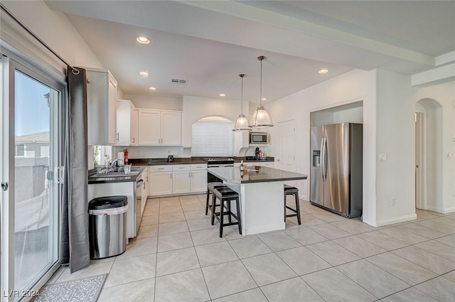 kitchen featuring appliances with stainless steel finishes, a kitchen island, a kitchen breakfast bar, white cabinetry, and pendant lighting