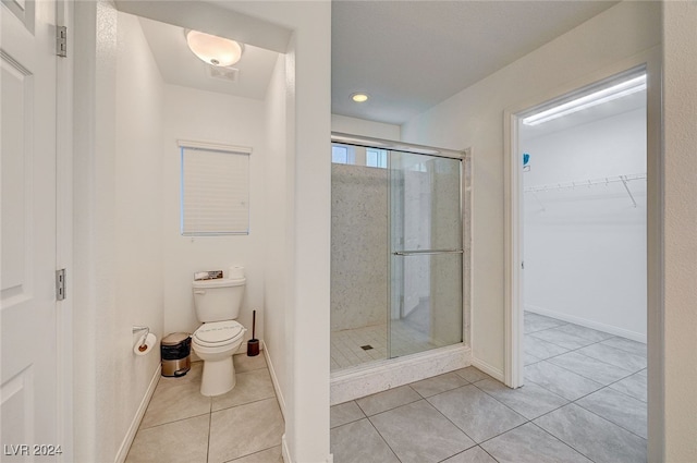 bathroom featuring tile patterned floors, toilet, and walk in shower