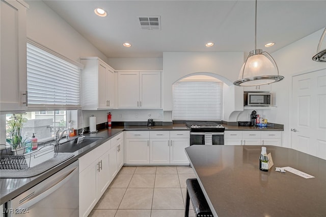 kitchen with sink, light tile patterned flooring, stainless steel appliances, decorative light fixtures, and white cabinets