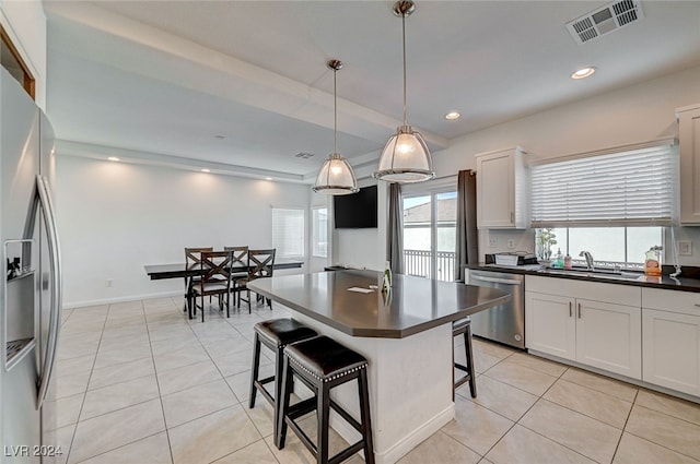 kitchen featuring a kitchen breakfast bar, white cabinets, stainless steel appliances, and hanging light fixtures